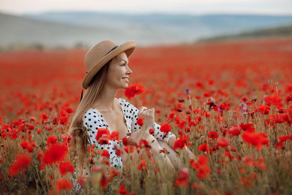 A girl smiling sitting in a field of flowers