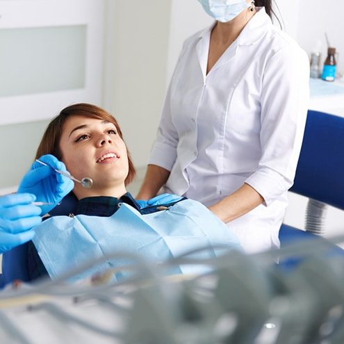 A Dentist With Assistant Inspecting a Woman's teeth at an emergency appointment