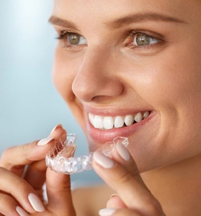 A client smiling holding Invisalign orthodontics at Dental Haus